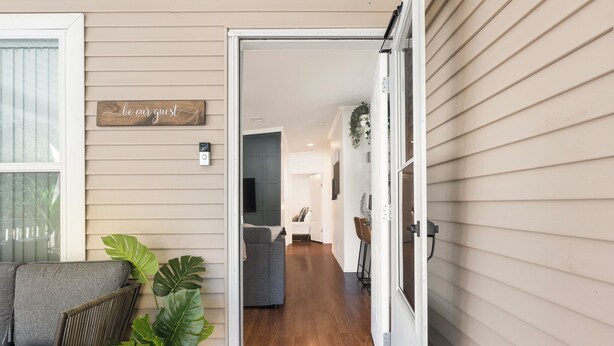 A home interior with a doorway leading to a living room, a sofa, and a potted plant. - Bright 4BR Home - Just Minutes from town & Beach! (St. Augustine)