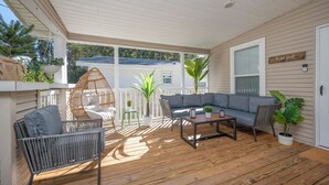 A covered porch with a gray sofa, wicker chairs, a coffee table, and potted plants. - Bright 4BR Home - Just Minutes from town & Beach! (St. Augustine)