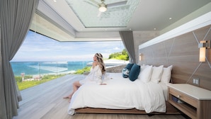 A modern bedroom with a large bed, a wooden headboard, and a view of the ocean. - Ultimate Luxury Villa: Hot Tub, Gourmet Kitchen & Stunning Ocean Views - Fully Staffed (Tamarindo)