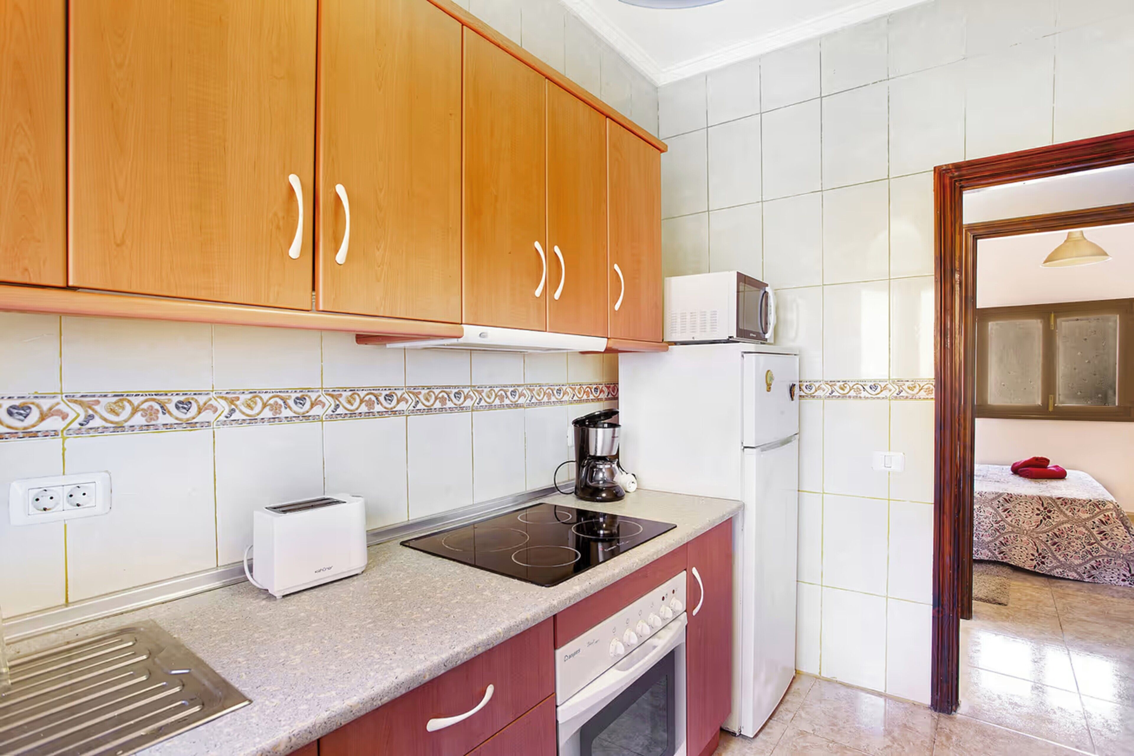 A kitchen with wooden cabinets, a built-in microwave, a toaster, and a stove.
