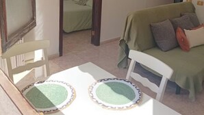 Ein Zimmer mit einem Bett, einem Sofa, einem Esstisch mit Platzsets und einem Spiegel an der Wand.