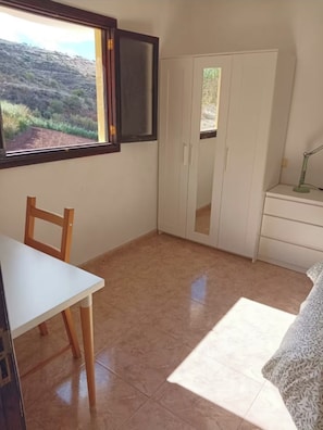 A small room with a white table and chair, a wardrobe, and a desk with a lamp. - Villa Palomino - Sleeps 6 - Parking - Pet Friendly (Galdar)