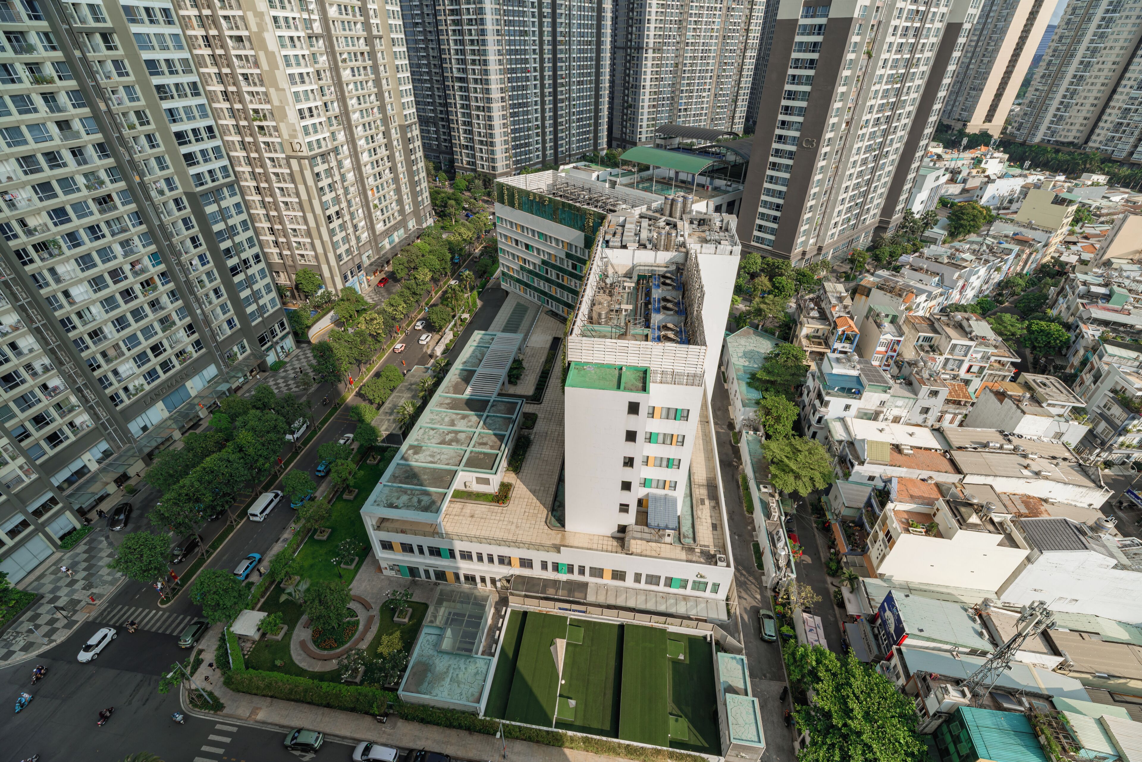 Ein Hochhaus mit mehreren Stockwerken, umgeben von anderen hohen Gebäuden, mit Dachgarten und Sportplatz.