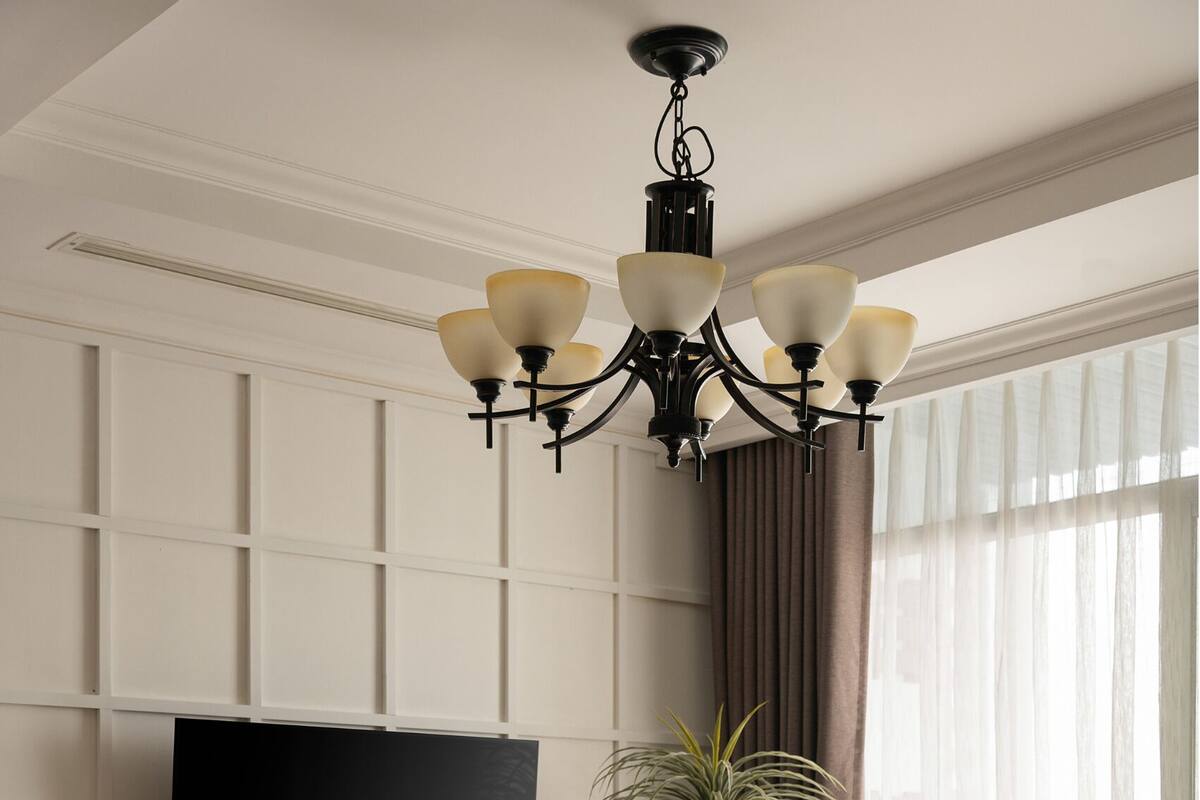 Una sala de estar moderna con una televisión de pantalla plana, muebles de madera, una lámpara de araña y un amplio ventanal con cortinas.