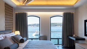 Ein modernes Hotelzimmer mit einem großen Bett, einem Schreibtisch und Blick auf das Wasser.