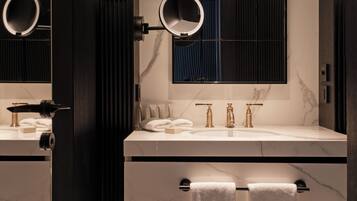 Un baño moderno con encimera de mármol, doble lavabo y dos dispensadores de toallas.