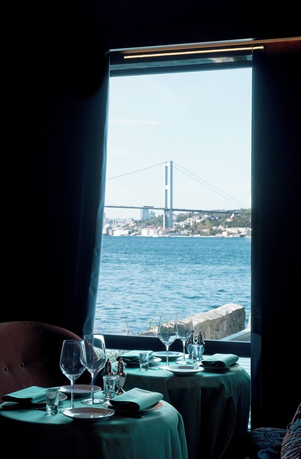 Mesa lista para comer con vista a un puente y al agua.