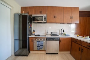 Kitchen area with a refrigerator, microwave, oven, and dishwasher.