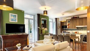 Ein modernes Wohnzimmer mit einer Couch, einem Fernseher und einem Essbereich mit Stühlen und einem Tisch.
