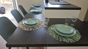 A dining table set with green plates, clear glasses, and a black countertop with a sink. - Destro village  (Lindoso)