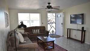 A living room with a brown sofa, a coffee table, a TV, and a ceiling fan.