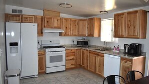 A compact kitchen with wooden cabinets, a white refrigerator, a stove, a microwave, and a dishwasher.
