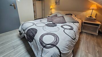 A bedroom with a bed, two bedside lamps, a wooden nightstand, and a wall-mounted coat rack.
