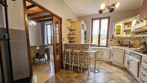 Une cuisine avec un coin bar, des tabourets en bois et une vue sur l’extérieur par une fenêtre.