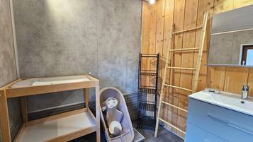 A bathroom with a wooden vanity, a small shelf, a toilet, and a ladder.