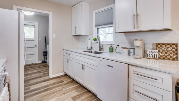 A modern kitchen with white cabinets, a wooden floor, a built-in sink, and a coffee bar area. - •new• Grace’s Getaway - sleeps 6 (Derby)