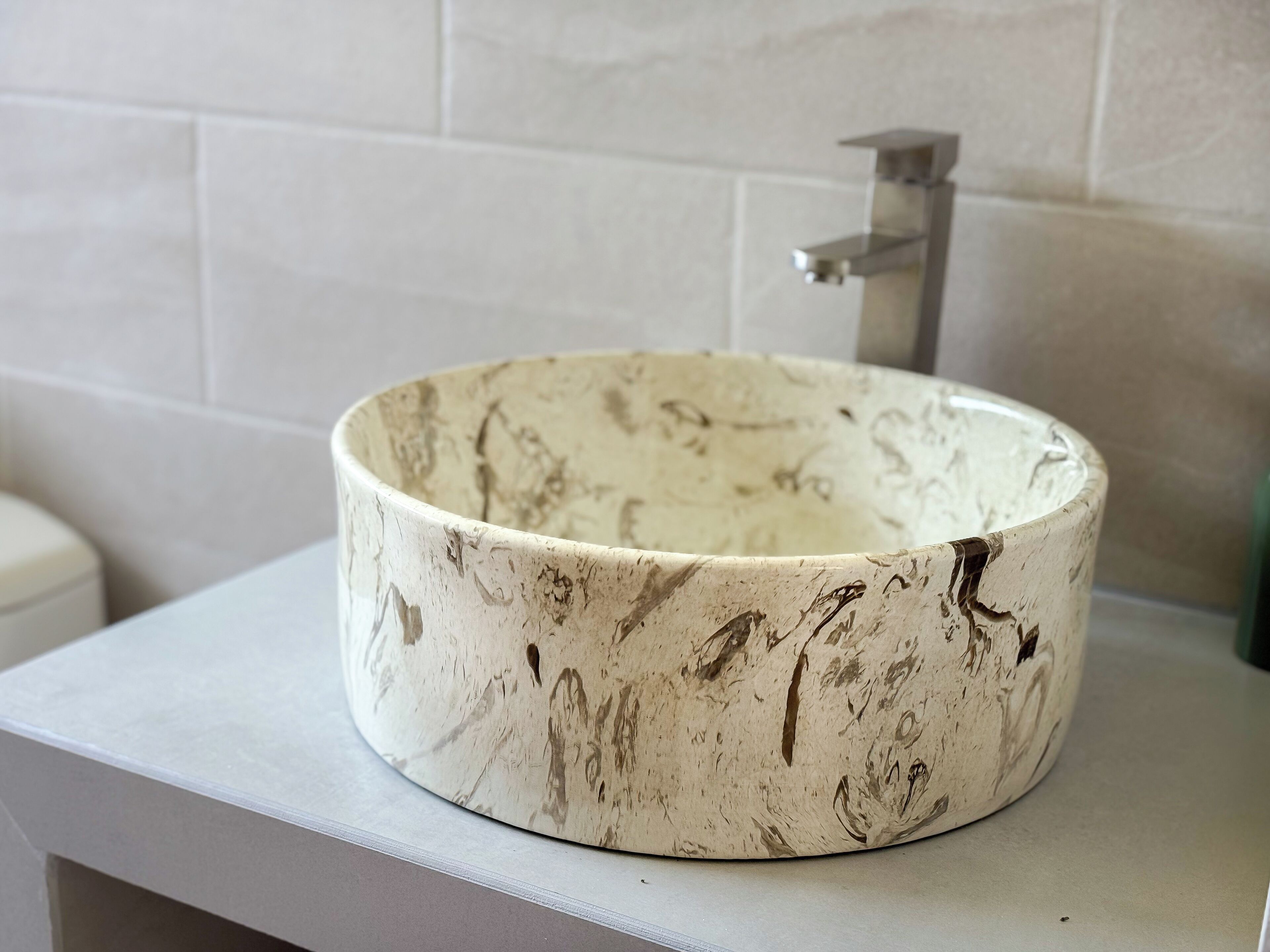 A bathroom with a round, textured sink on a white countertop.