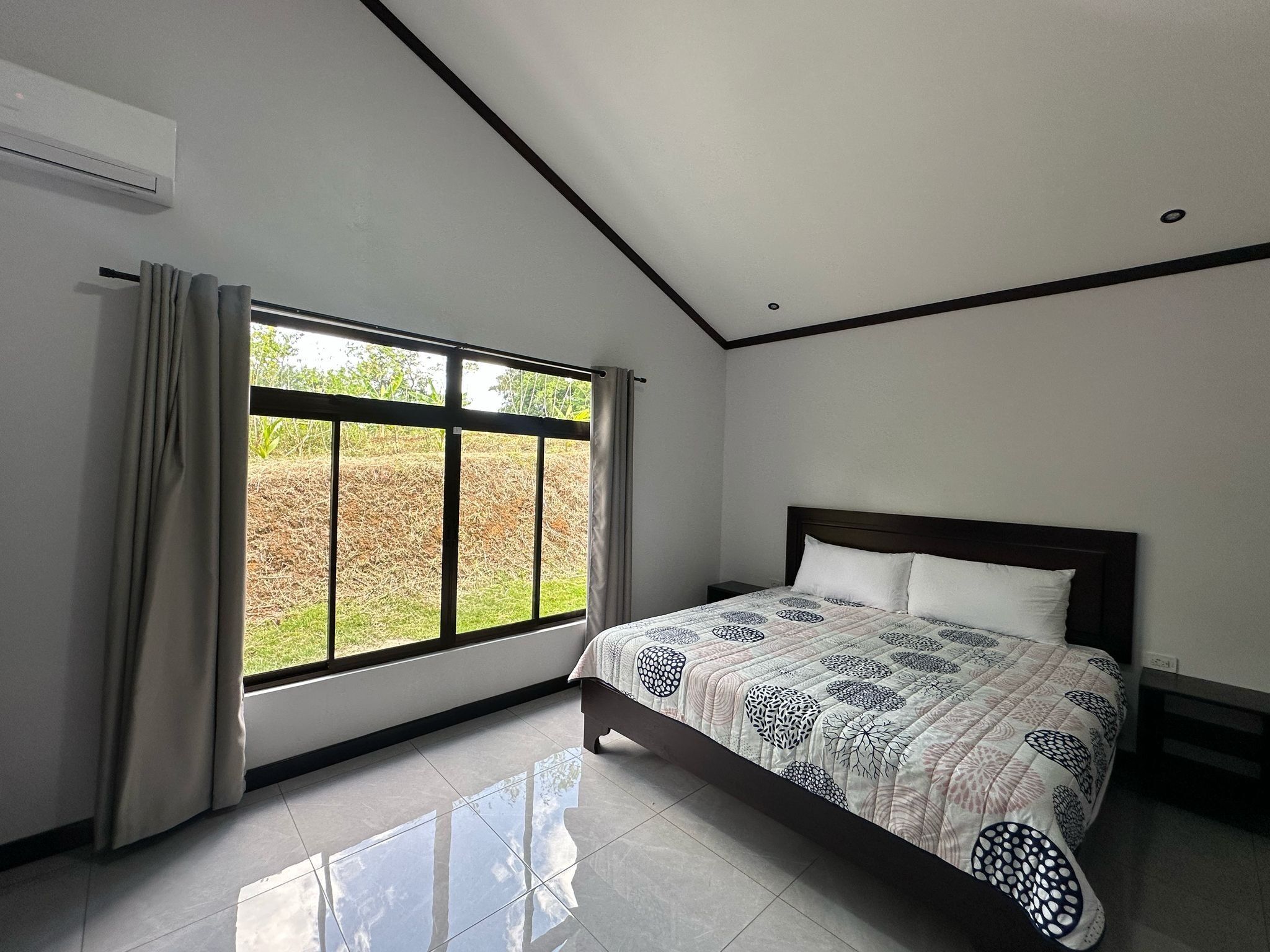 A bedroom with a bed, a window with curtains, and a ceiling fan.