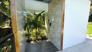 A modern shower area with a tiled wall, a wooden frame, and a shower head. - Oro Verde Lodge (Peñas Blancas)