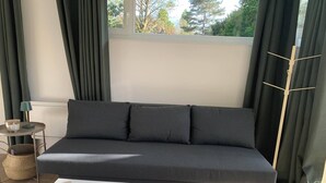 Un salon moderne avec un canapé gris, une table basse blanche et une fenêtre avec des rideaux.