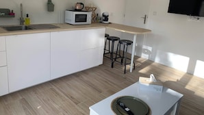 Une cuisine moderne équipée d’un four à micro-ondes, d’un évier et de tabourets de bar.