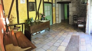 Une pièce au décor traditionnel, avec des poutres apparentes, un banc en bois, une porte verte et un mur en pierre.