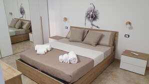 Un dormitorio moderno con una cama de madera, ropa de cama color beige y una mesita de noche con un control remoto.