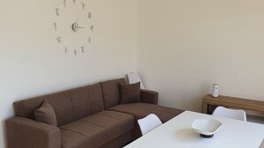 Una sala de estar moderna con un sofá marrón, una mesa de comedor blanca y un reloj de pared minimalista.