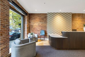Een receptiezone met een bakstenen muur, behang met een patroon en een receptiebalie.