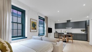 A modern bedroom with a large bed, a small dining area, and a kitchenette. - The Mercer Boutique Hotel (Montréal)