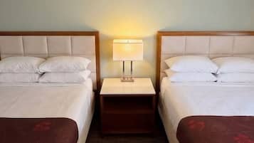 Ett hotellrum med två sängar, ett nattduksbord med en lampa och en sänggavel i trä.