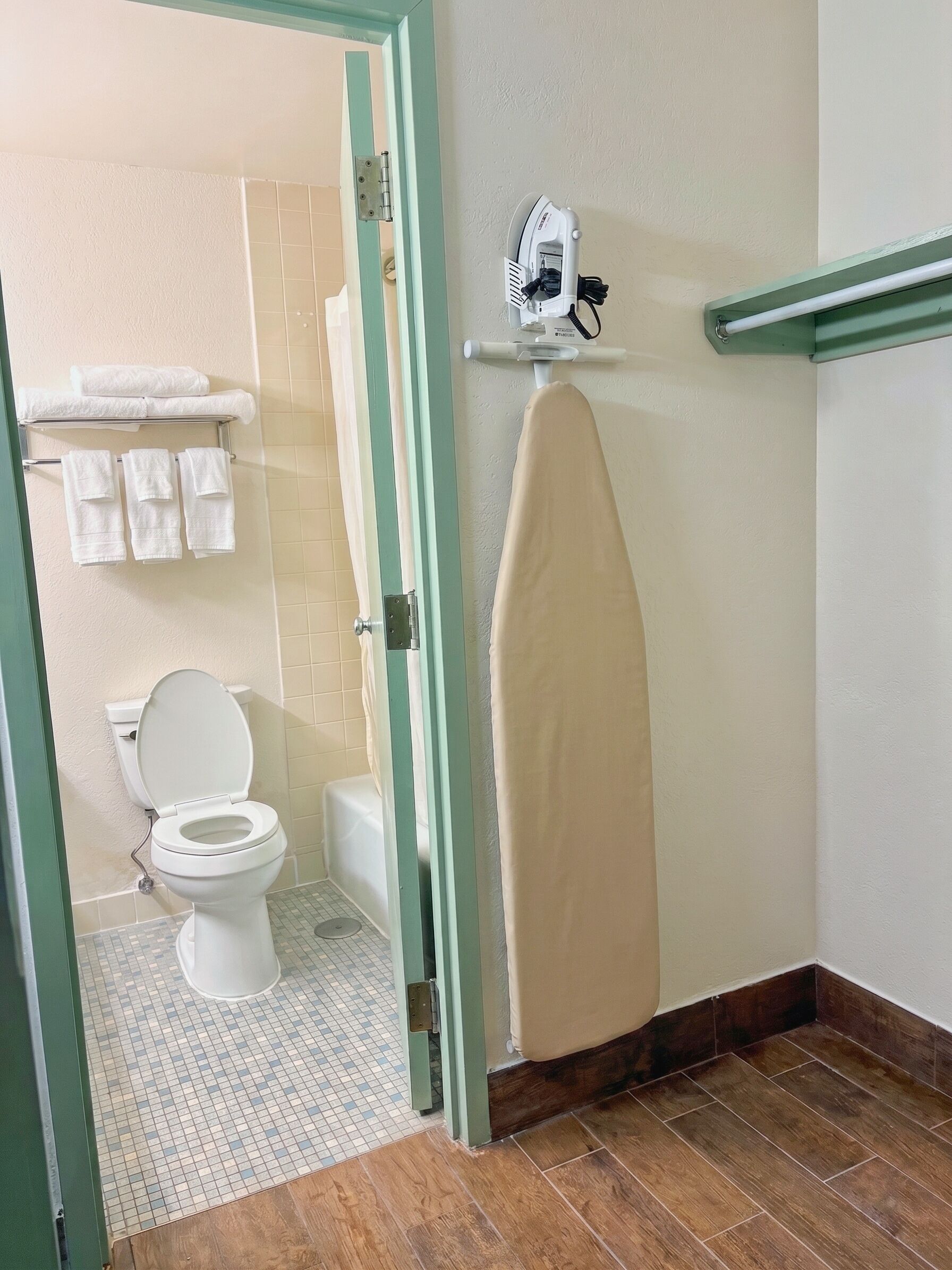 Un bagno con un WC, doccia e un portasciugamani con asciugamani.
