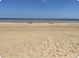 A wide sandy beach with a clear blue sky.