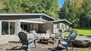 A modern house with a stone fire pit and outdoor seating area. - The Woodland Haven - Secluded 3 bed, 2 bath, and Hot Tub! (Great Valley)