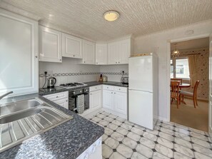 A kitchen with white cabinets, a gas stove, a sink, and a refrigerator.