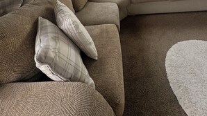 A cozy living room with a sectional sofa, multiple pillows, and a large window with curtains. - Marine Getaways Caravan Hire

A home from home experience in luxury.. (Rhyl)