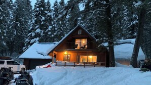 Una baita con un balcone, circondata da alberi innevati.