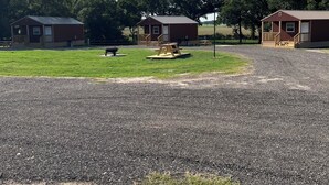 A gravel parking area with two small cabins and a picnic table. - Cabin Unit 3 of 6 Called the Texan with WiFi and AC in serene Paige (Paige)