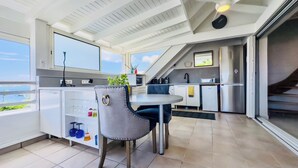 Une cuisine moderne avec un coin repas, de grandes fenêtres et une vue sur la mer.