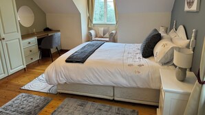 Um quarto com uma cama grande, uma escrivaninha, uma cadeira e uma janela.