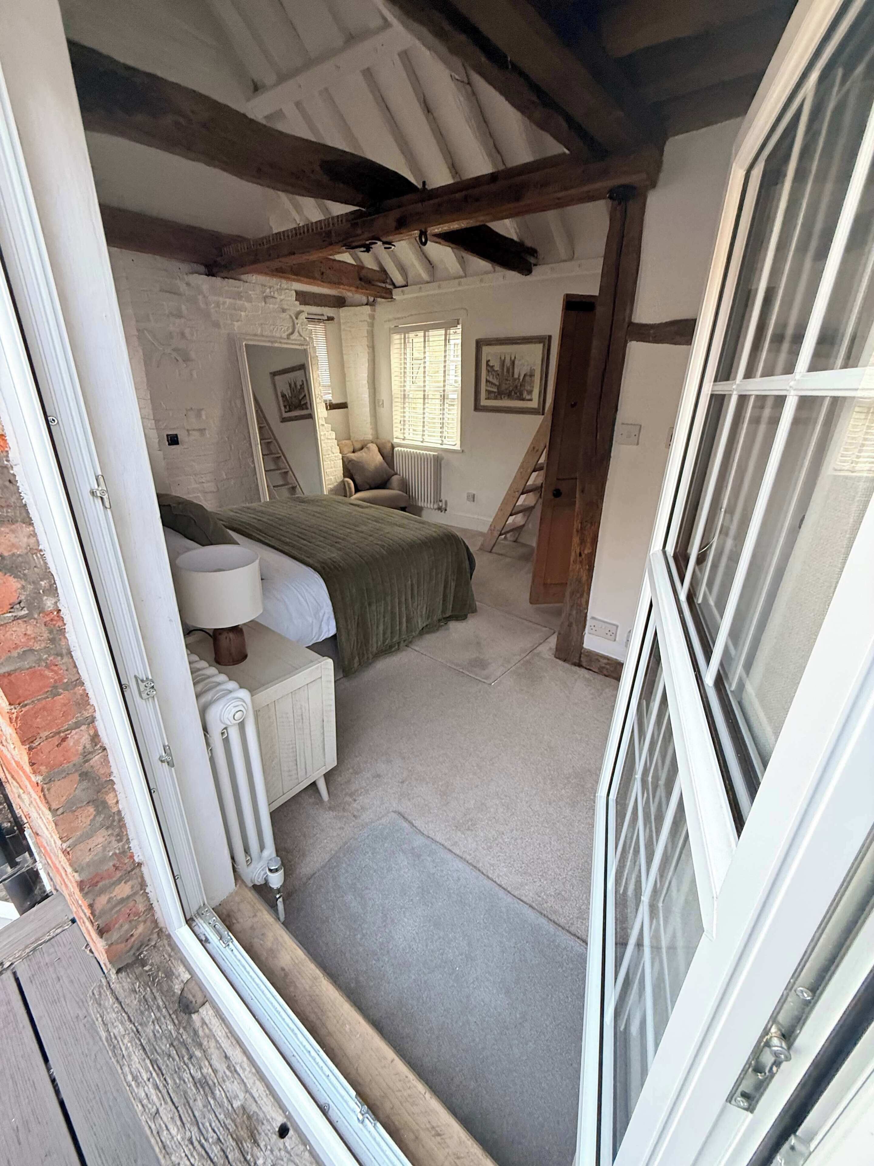 Ein Schlafzimmer mit Bett, Heizkörper, Fenster und Tür.