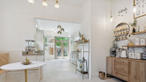 A modern kitchen with white cabinetry, a round white table, and pendant lighting.