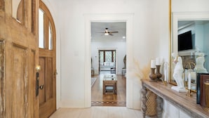 A hallway with a wooden door, a small table, and a mirror with decorative items.
