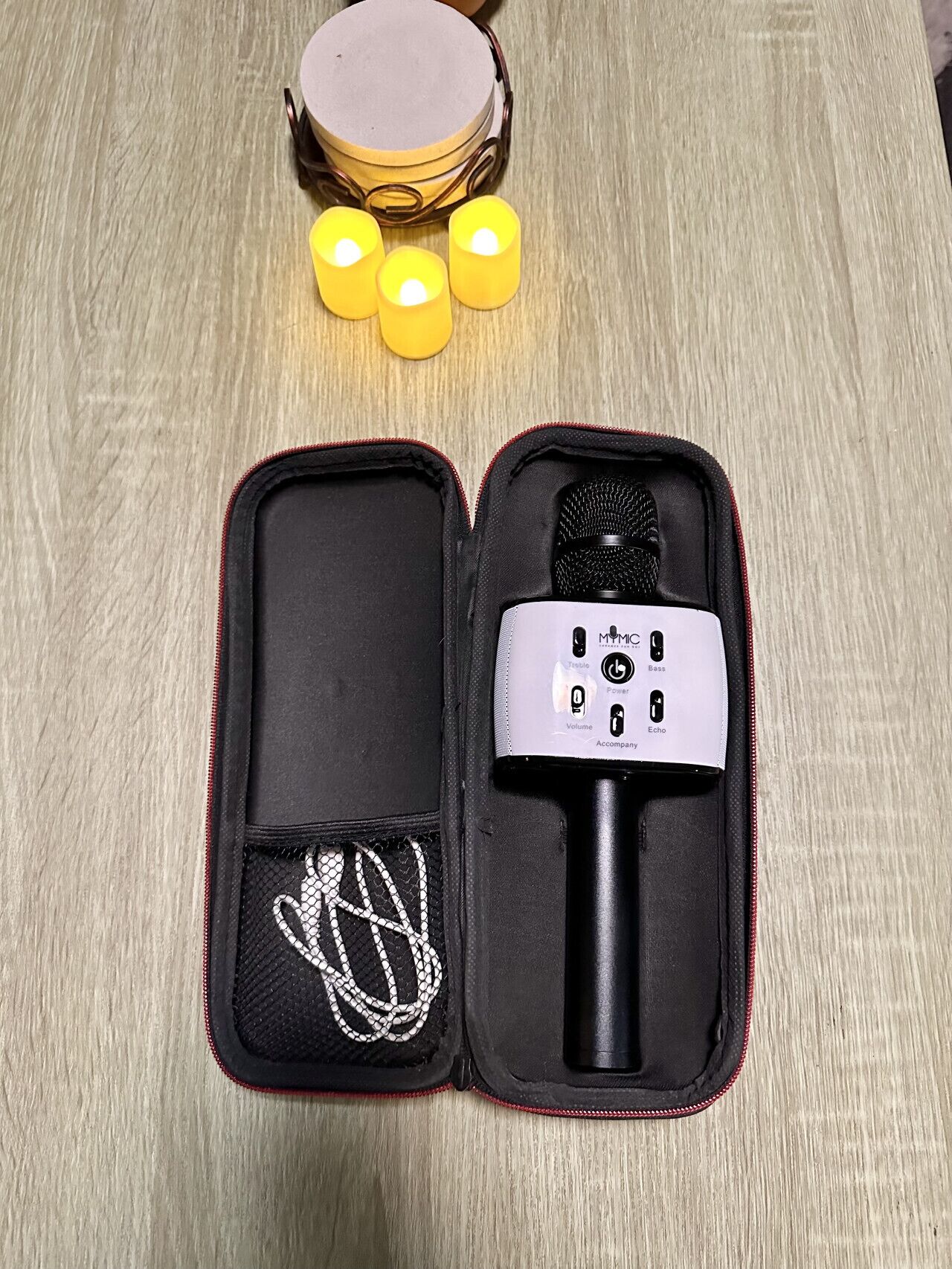 Un étui pour microphone ouvert contenant un microphone, un adaptateur secteur et un câble.