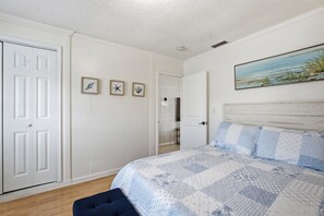 A bedroom with a bed, a door, and a wall with three framed pictures.