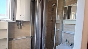 Un baño compacto con cabina de ducha, lavabo e inodoro.