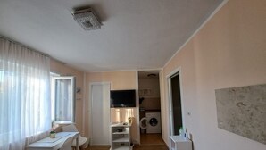 Un espacio habitable compacto con comedor, kitchenette y zona de lavandería.