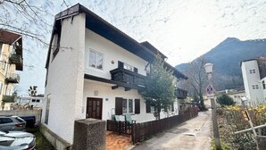 Un edificio blanco de dos pisos con balcón, un camino de entrada pavimentado y un letrero de no estacionamiento.