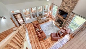 A spacious living room with a fireplace, wooden flooring, and large windows. - Creekside screened porch, pet friendly, minutes to downtown Hayesville. Firewood (Hayesville)