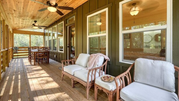 A covered porch with wooden flooring, wicker furniture, and large windows. - Creekside screened porch, pet friendly, minutes to downtown Hayesville. Firewood (Hayesville)